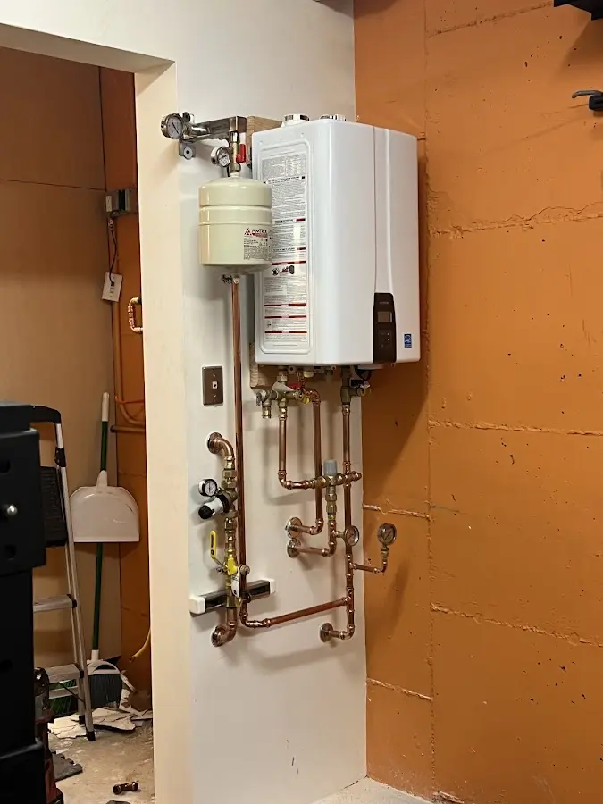 Plumbing technician inspecting water heater connections in Rochester Hills